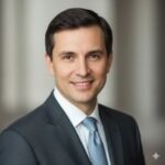 Портрет русского бизнесмена, уверенный взгляд, дружелюбная улыбка, профессиональная фотосессия в студии.